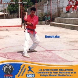 Lic. Arnoby Sinam Alba ejecutando técnicas con nunchaku durante una exhibición de artes marciales realizada en el Colegio Manuel Murillo Toro en 1991. Fotografía histórica de Arnoby Sinam Alba realizando una demostración con nunchaku durante una exhibición de artes marciales en el Colegio Manuel Murillo Toro en 1991.