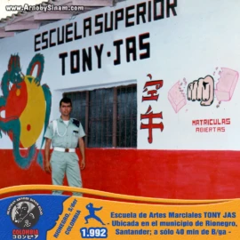 Fotografía histórica de Arnoby Sinam frente a la Escuela Superior Tony Jas en Rionegro, Santander, uno de los centros más representativos para la formación y difusión de las artes marciales en la región. Arnoby Sinam frente a la Escuela Superior Tony Jas ubicada en Rionegro, Santander, una institución dedicada a la enseñanza y promoción de las artes marciales en Colombia.