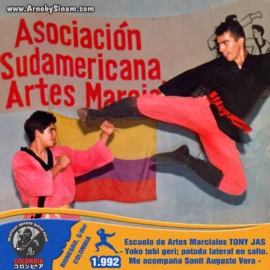 Arnoby Sinam realizando una espectacular yoko tobi geri (patada lateral en salto) durante una demostración en la Escuela de Artes Marciales Tony Jas, acompañado por Sonit Augusto Vera. Arnoby Sinam ejecutando una yoko tobi geri, o patada lateral en salto, durante una exhibición de artes marciales en la Escuela Tony Jas en 1992, acompañado por Sonit Augusto Vera.
