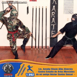 Arnoby Sinam participa en una demostración de técnicas ninja junto a Héctor Santos Sensei en el Centro de Estudio de Artes Marciales, fortaleciendo la amistad y el intercambio marcial. Demostración de combate ninja realizada por Arnoby Sinam y Héctor Santos Sensei en un dojo de artes marciales en Colombia durante 1992.