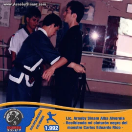 Momento histórico en el que Arnoby Sinam recibe oficialmente su cinturón negro de manos del maestro Carlos Eduardo Rico, culminando años de disciplina, entrenamiento y dedicación a las artes marciales. Arnoby Sinam recibe su cinturón negro de manos del maestro Carlos Eduardo Rico tras aprobar exitosamente su examen de grado en 1992.