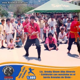Exhibición pública de artes marciales realizada por Lic. Arnoby Sinam Alba en el barrio Arenales de Girón, Santander, demostrando técnicas con nunchaku ante la comunidad en 1989. Fotografía histórica de Arnoby Sinam Alba realizando una exhibición con nunchaku en el barrio Arenales de Girón, Santander, en 1989.