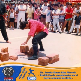 Exhibición pública de rompimientos realizada por Lic. Arnoby Sinam Alba en el barrio Arenales de Girón, Santander, demostrando técnicas tradicionales de artes marciales ante la comunidad en 1989. Fotografía histórica de Arnoby Sinam Alba realizando una exhibición de rompimientos durante una demostración de artes marciales en el barrio Arenales de Girón, Santander, en 1989.